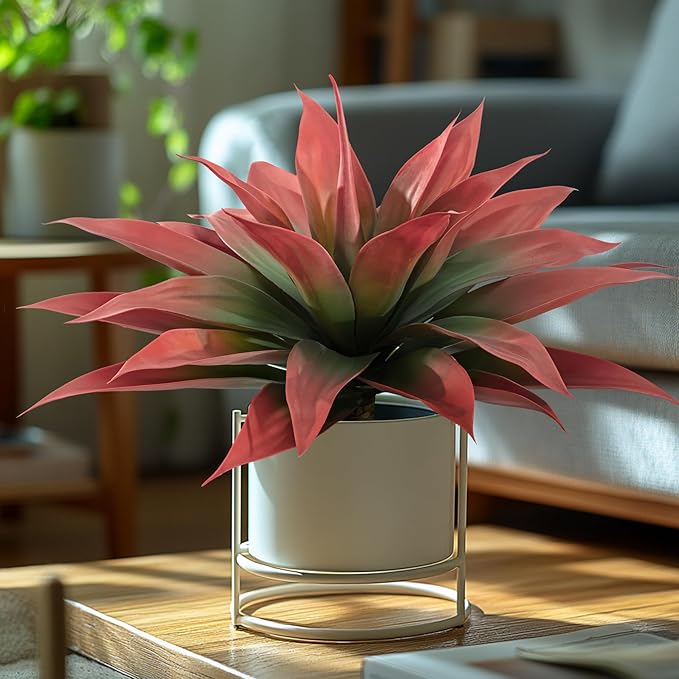 Red and green faux agave plant with spiky leaves in a gold planter stand