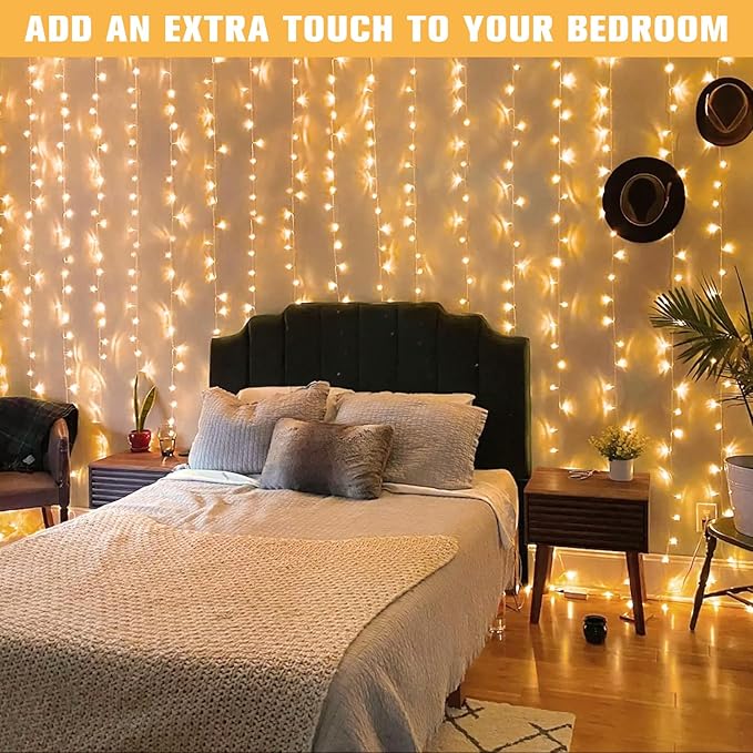 Warm white LED curtain string lights draped along a bedroom wall near the bed