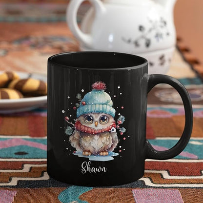 Black ceramic mug with winter owl illustration and 'Shawn' name, on colorful rug
