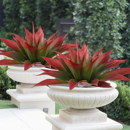 Two wine-red faux agave plants with green centers in white pedestal planters