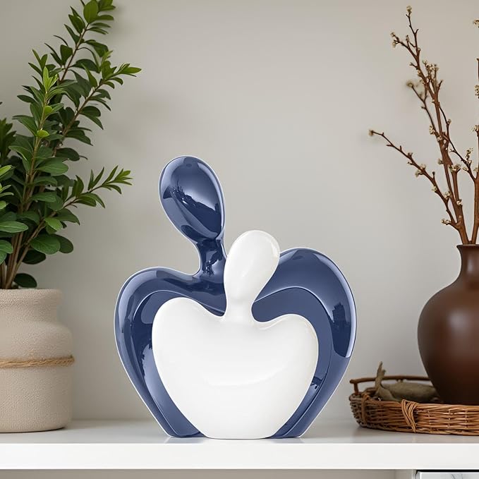 Glazed blue and white ceramic couple figurines, abstract hugging heart shape design.