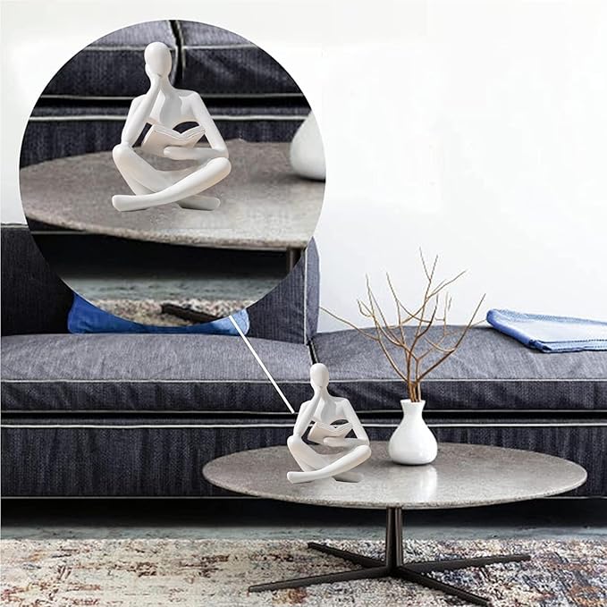 White seated reading thinker resin statue on a round coffee table, holding a book