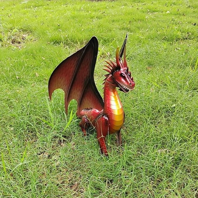 Red dragon statue on grass, side angle with wings open and curved tail