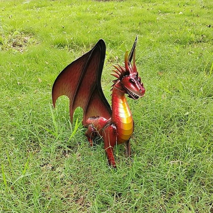 Red dragon statue on grass, side angle with wings open and curved tail