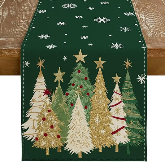 Green Christmas table runner with snowy pine trees, gold stars, and white snowflakes.