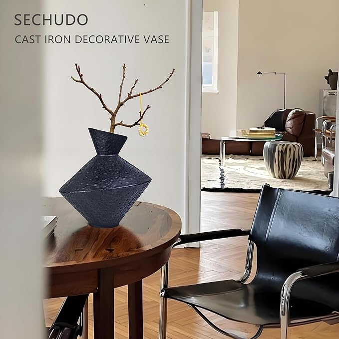 Angled-neck cast iron decorative vase with hammered texture on a wooden tabletop