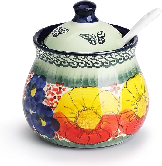 Glazed ceramic sugar jar with navy lid and spoon; hand-painted blue, yellow, red flowers.