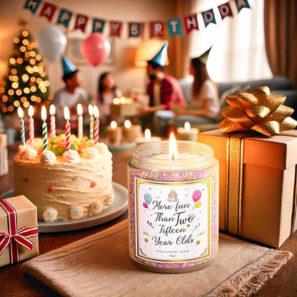 9 oz birthday candle jar with gold lid, flame lit, on table with wrapped gifts