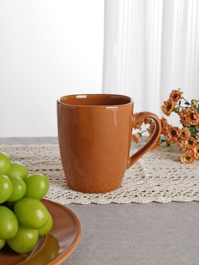 Brown stoneware coffee mug with glossy reactive glaze and curved handle, close-up