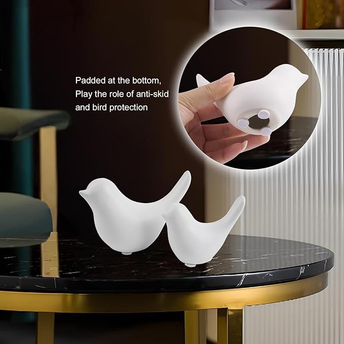Ceramic white bird figurine set of 2 on glass tabletop with inset of hand holding one