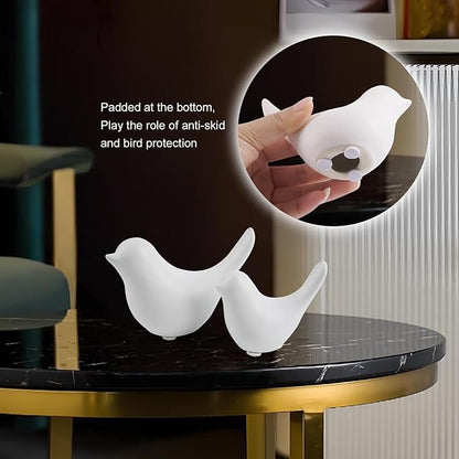 Ceramic white bird figurine set of 2 on glass tabletop with inset of hand holding one