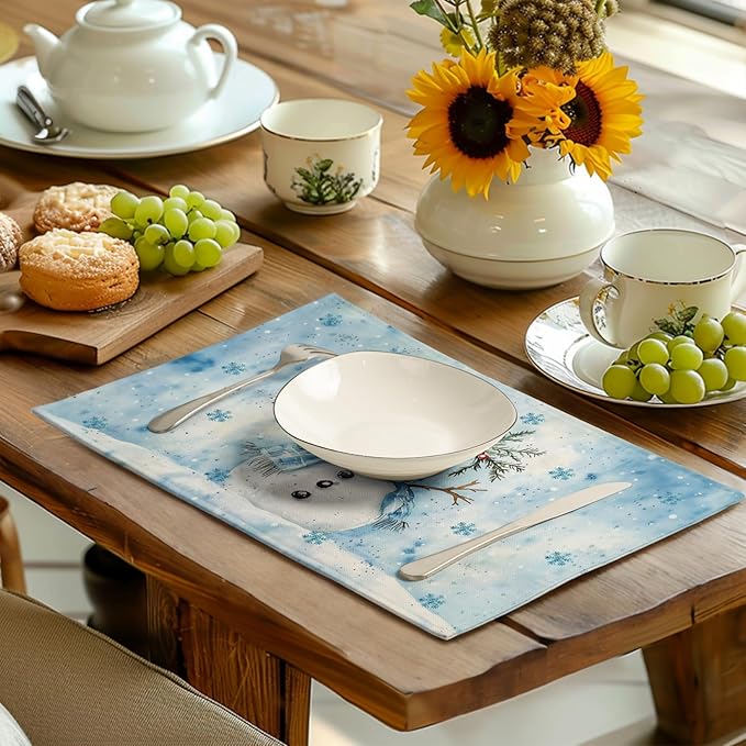 Blue snowman winter placemats set of 4 on dining table with place settings.