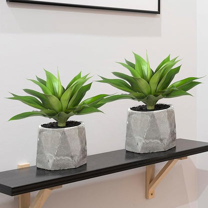 Two green faux agave plants with spiky leaves in gray textured planters