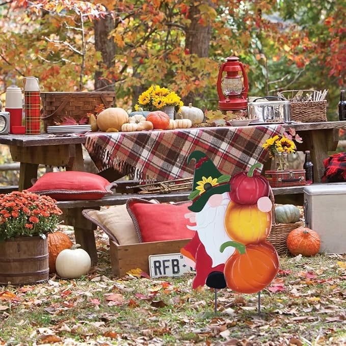 Metal gnome pumpkin stake in front of outdoor table decor, red and yellow pumpkin shapes