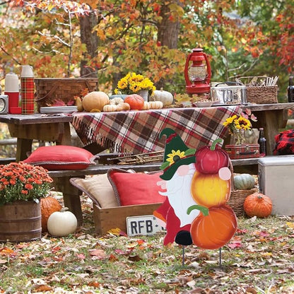 Metal gnome pumpkin stake in front of outdoor table decor, red and yellow pumpkin shapes