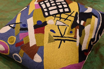 Abstract embroidered pillow cover detail with yellow shapes and black grid blocks