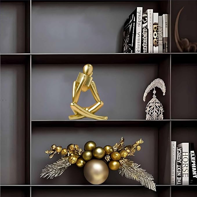 Gold resin reading figurine on shelf, seated cross-legged pose