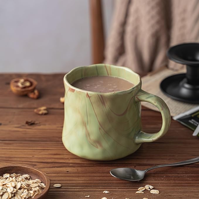 Mint green ceramic coffee mug with abstract red and white artwork and sturdy handle
