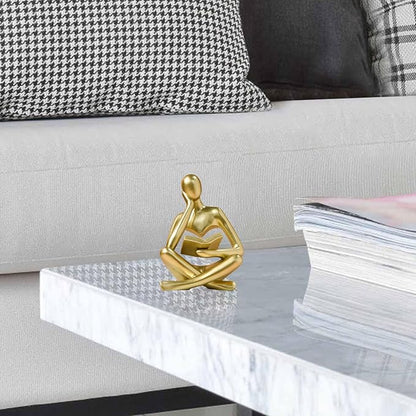 Gold resin seated thinker figurine reading an open book, front view