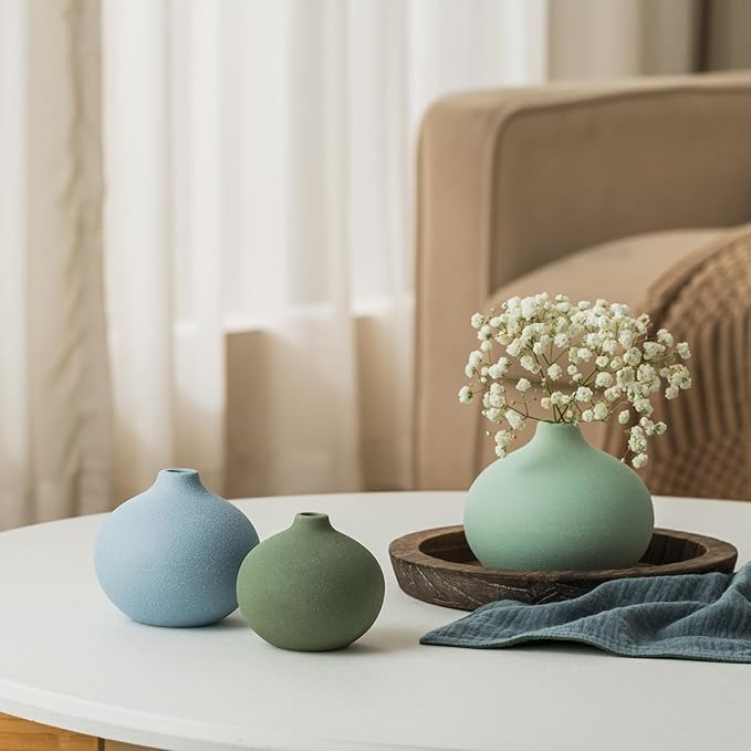 Three mini ceramic bud vases in soft pastels with a small white flower bouquet