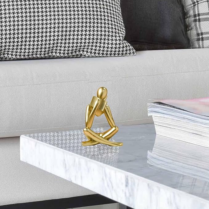 Gold resin reading figurine on white ledge, seated cross-legged with book