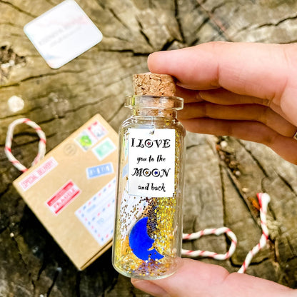 Corked miniature bottle with blue moon label, held in hand with gift box
