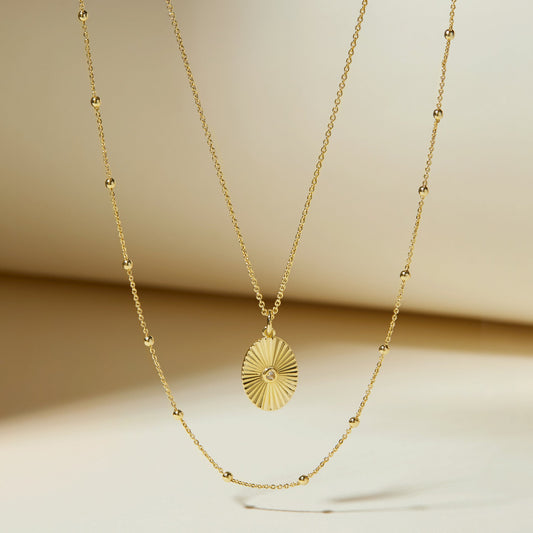 Gold oval pendant necklace set with satellite bead links on fine chain