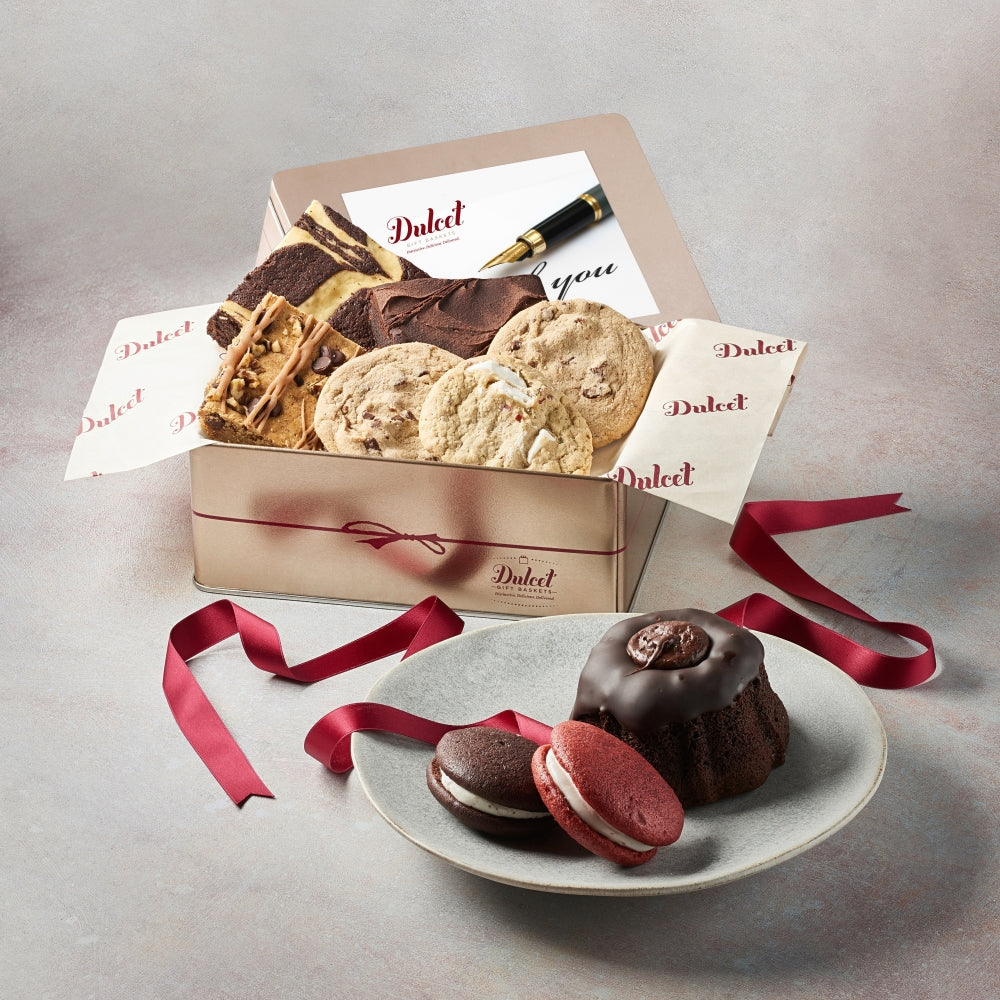 Assorted sweets gift tin with ribbon, chocolates and cookies on a plate