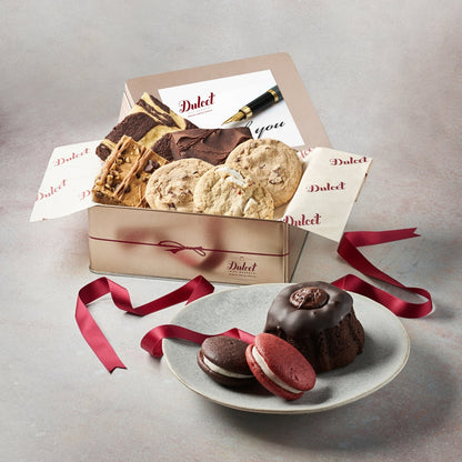 Assorted sweets gift tin with ribbon, chocolates and cookies on a plate
