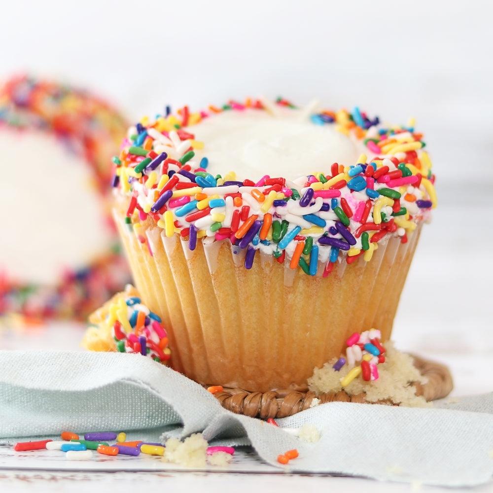 Vanilla cupcake with colorful rainbow sprinkles and white frosting