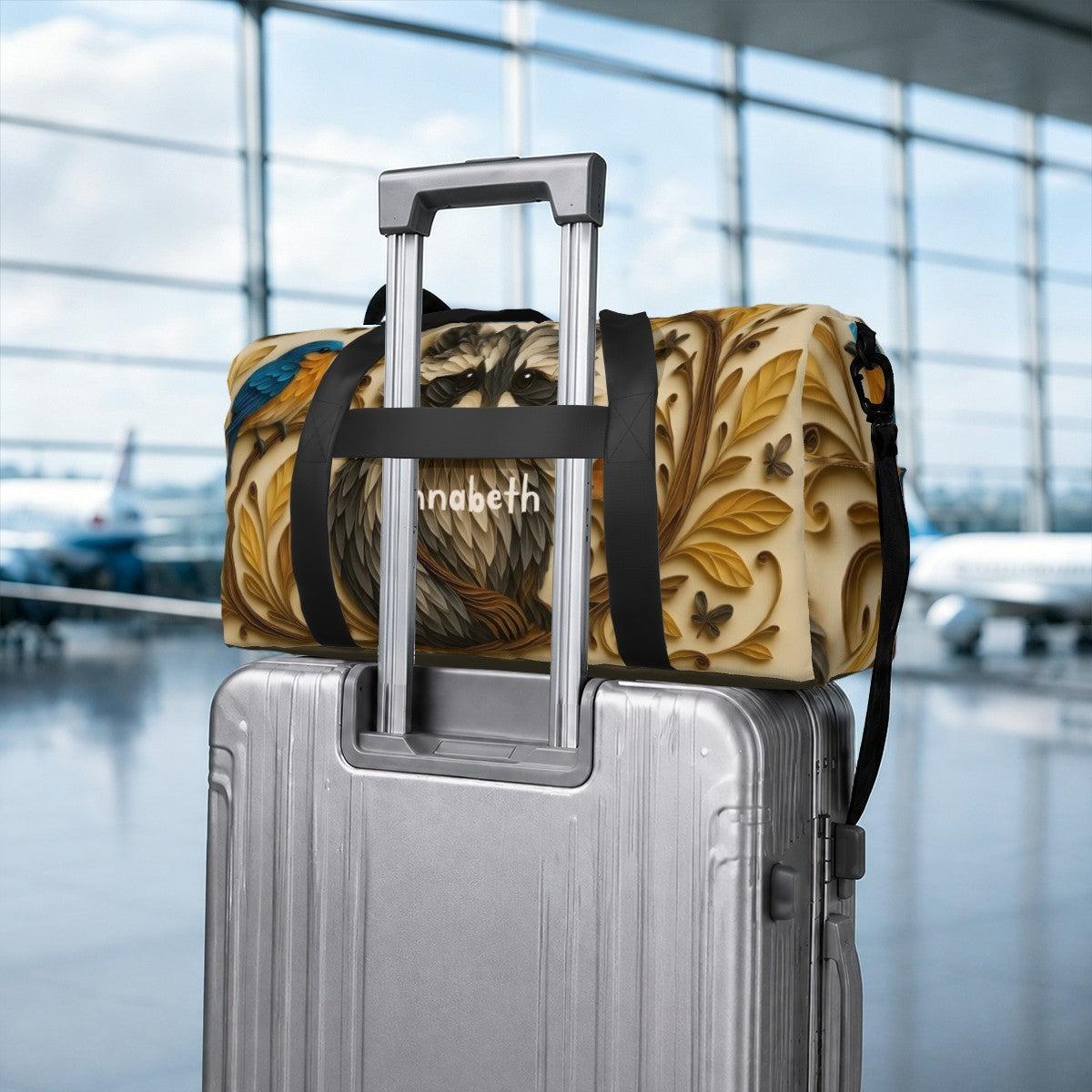 Raccoon print duffel bag secured on a rolling suitcase with black strap