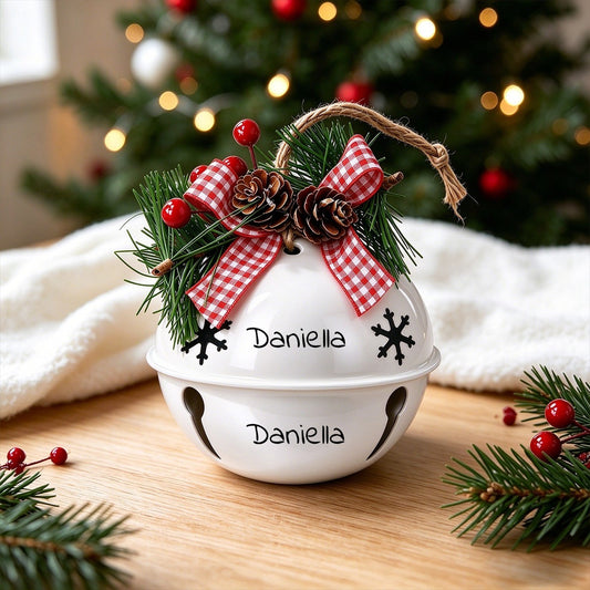 White holiday jingle bell ornament with red plaid bows, pine, and pinecone accents