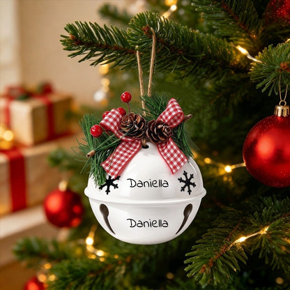 White holiday jingle bell ornament hanging on pine branches with red plaid bows