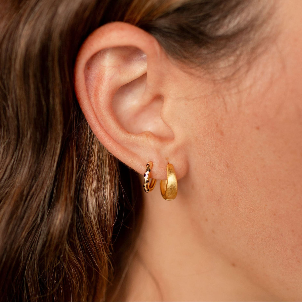 Black-dotted gold vermeil hoop worn beside a plain gold hoop