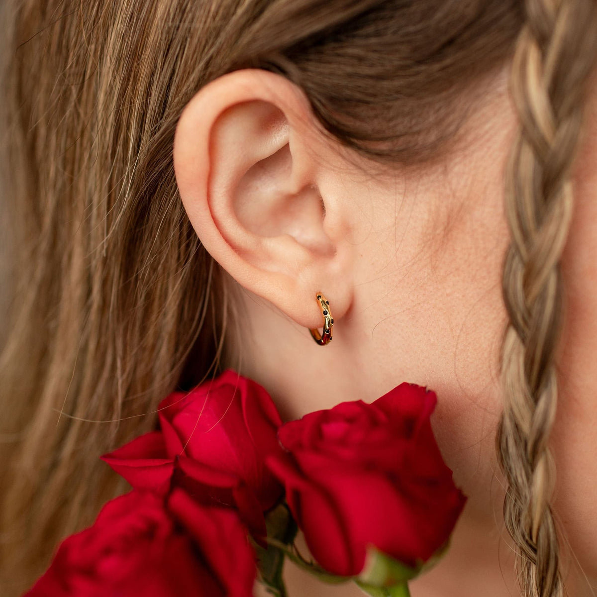 Gold vermeil hoop with black imitation onyx dots worn on an ear