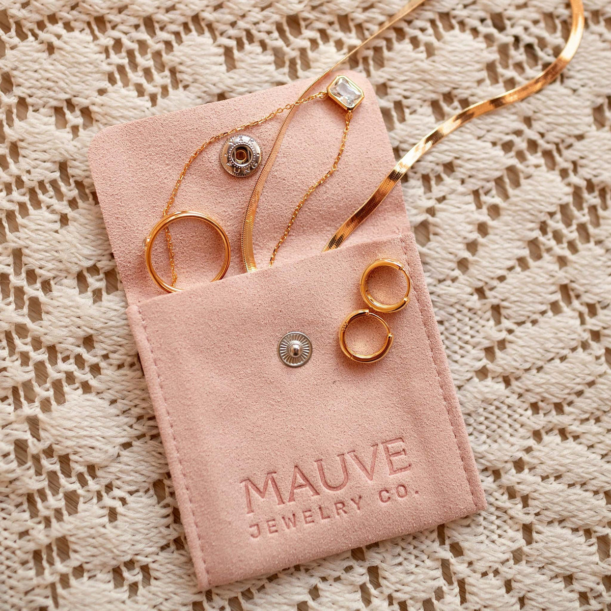 Gold hoop earrings with raised dot details among assorted jewelry in a pouch