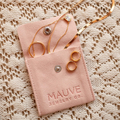Gold hoop earrings with raised dot details among assorted jewelry in a pouch
