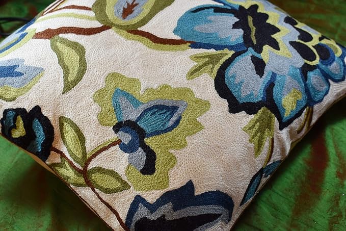 Decorative cream pillow cover with blue floral needlepoint and dark outline accents