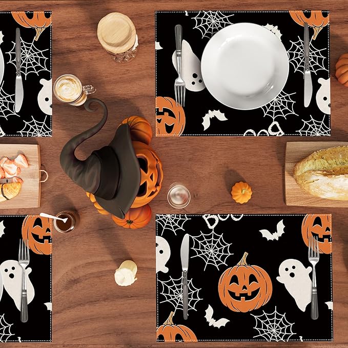 Halloween placemat set: black table mat with pumpkin faces, ghosts, bats, and spiderweb pattern.