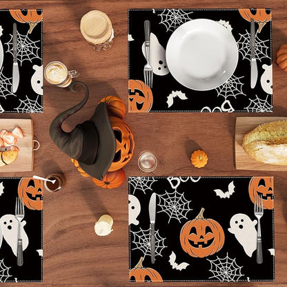 Halloween placemat set: black table mat with pumpkin faces, ghosts, bats, and spiderweb pattern.