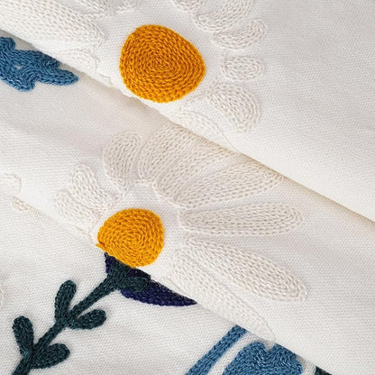 Close-up of white cotton pillow cover embroidery with yellow dot flowers and blue vines