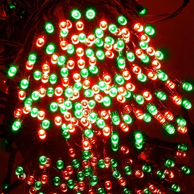 Glowing red and green LED Christmas string lights on black wire, close-up