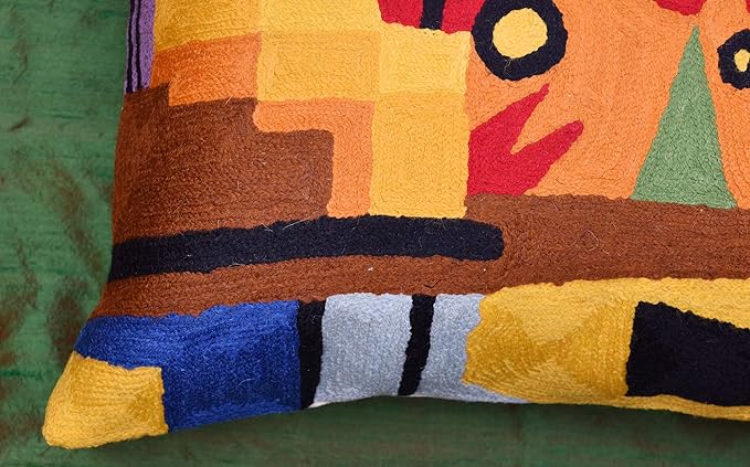 Lower corner of red abstract embroidered pillow cover with checker blocks and navy trim
