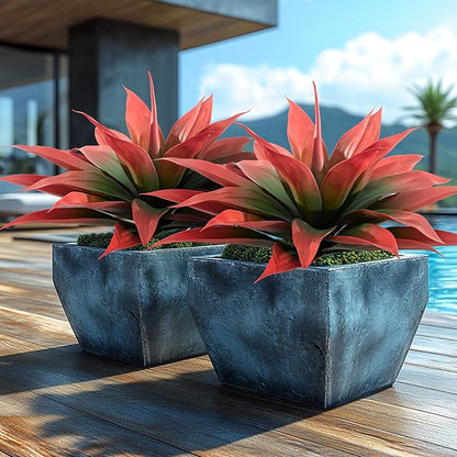Two red and green faux agave plants in blue fabric-like planters on a wooden deck