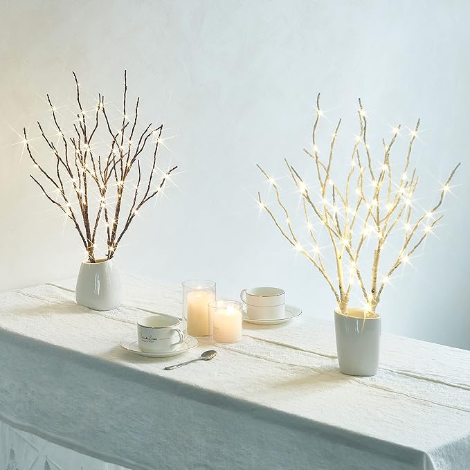 Pair of brown and lit willow branches in white vases with warm white fairy lights