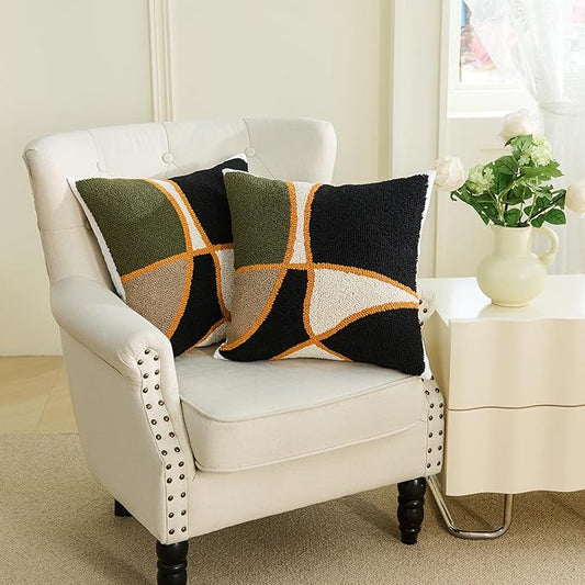 Two square tufted pillow covers on white chair, green/black/tan cross with orange trim