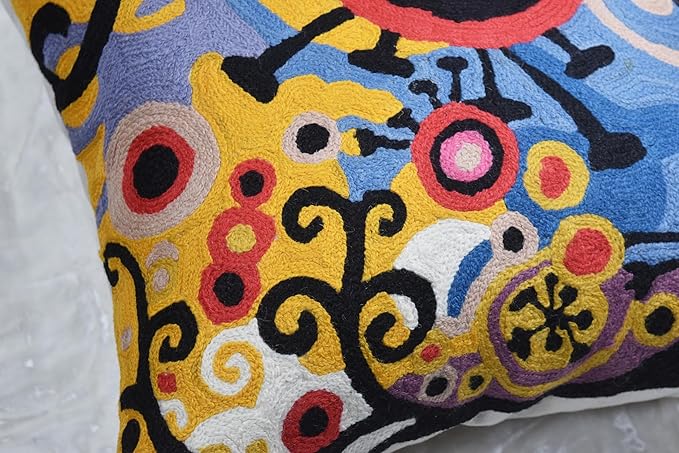 Embroidered pillow cover corner detail with dense multicolor abstract motifs and circular accents.