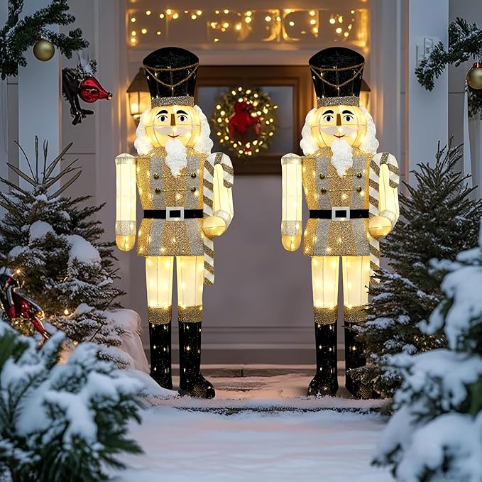 Two lighted nutcracker yard decorations with gold coats, white fur, black hats, glowing LEDs