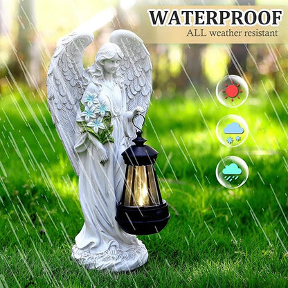 White angel solar garden statue with wings beside an illuminated lantern