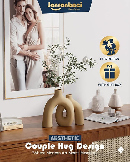 Matte tan-brown ceramic couple hug vase with donut-shaped cutouts, angled view.